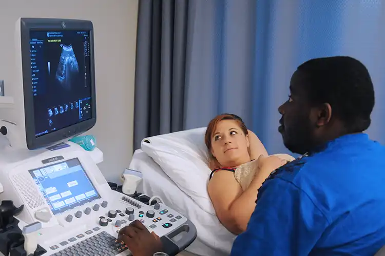 A student takes an ultrasound of another student's abdomen.