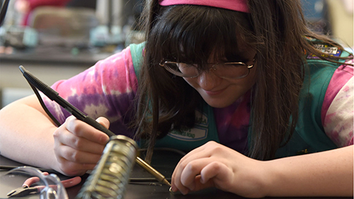A girl soldering a piece of hardware